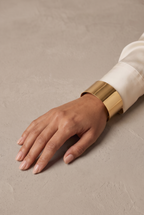 Plain wide polished cuff bangle in gold worn on the wrist