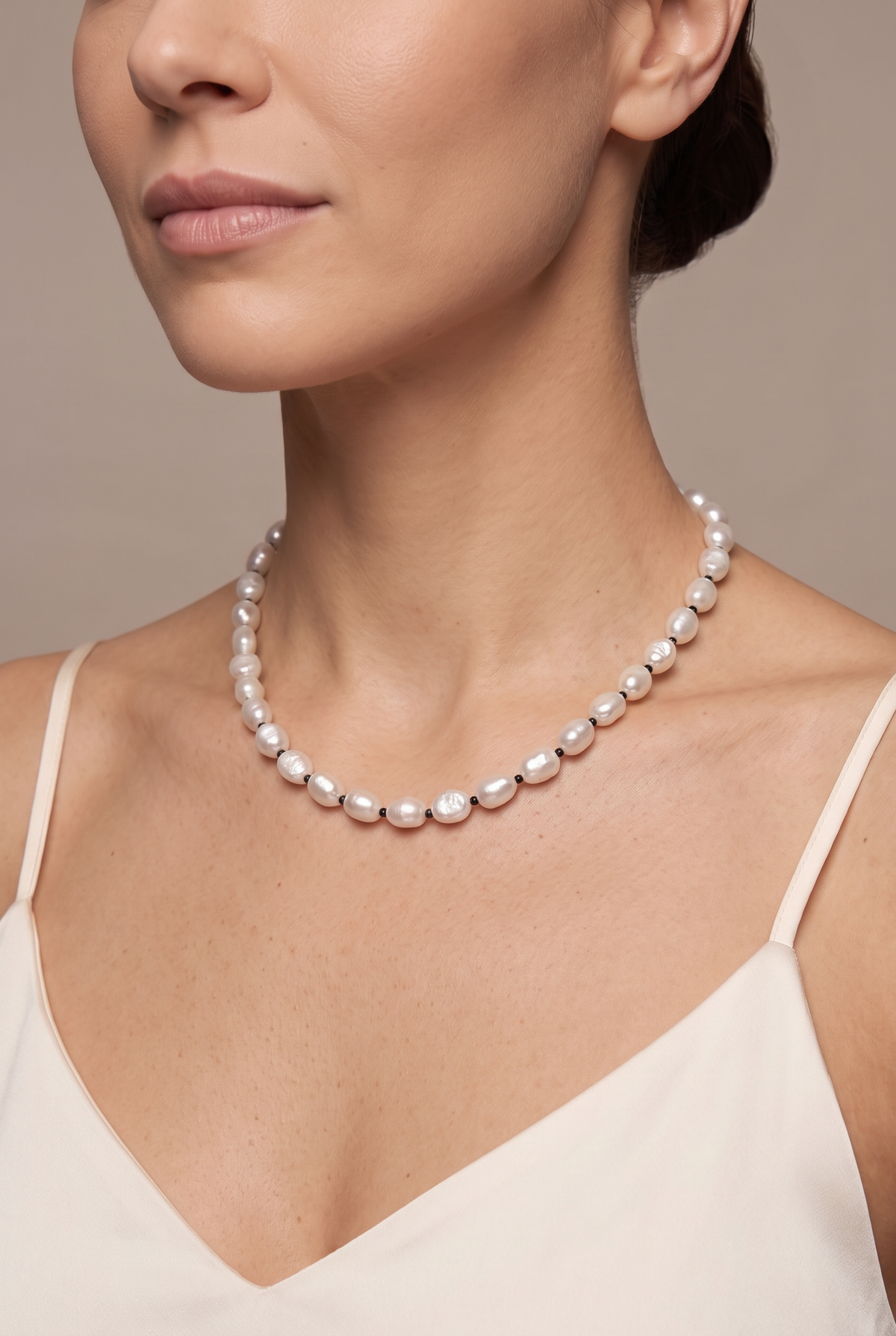 White baroque pearl necklace with black spacers worn at the collarbone